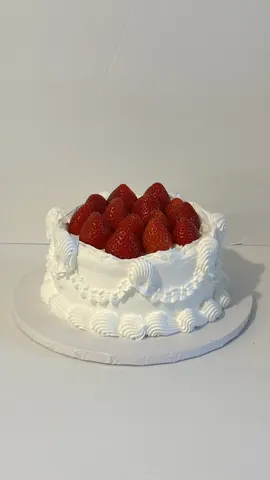 White vintage cake with piped shells and garlands, topped with fresh strawberries.